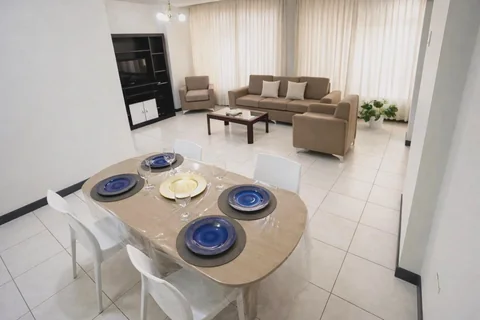 Comedor preparado con vajilla junto a una sala